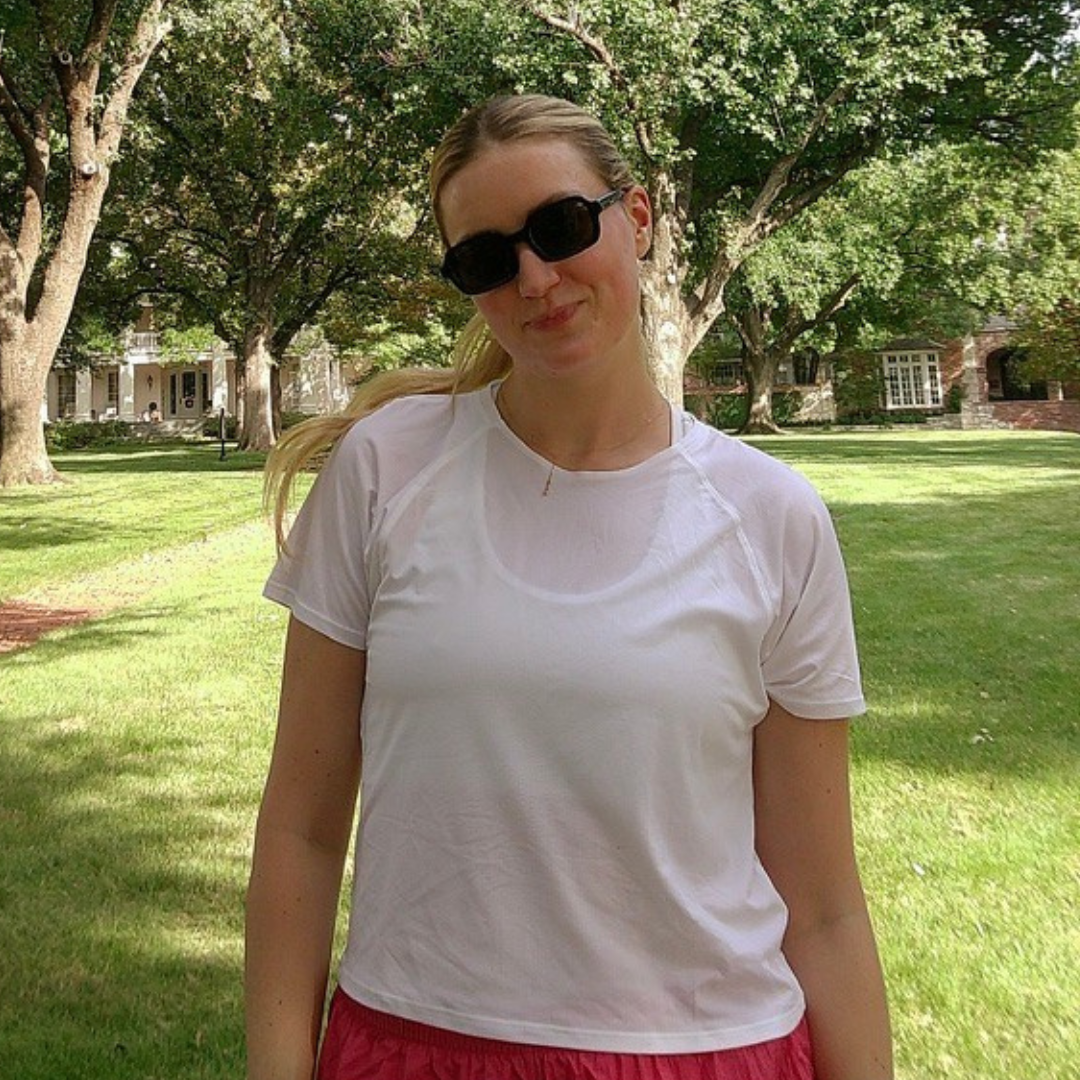 Woman wearing sunglasses and a white t-shirt in a park setting