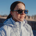 Woman wearing sunglasses and a light blue jacket on a clear day